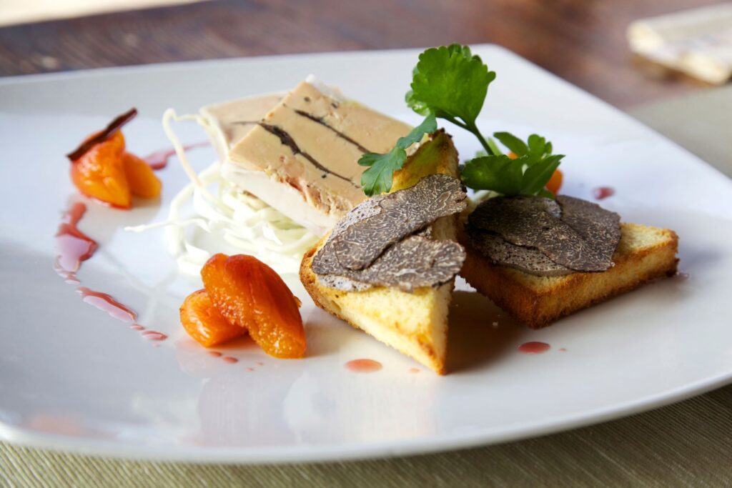 two slices of foie gras with toasted bread and black truffle with dry apricots